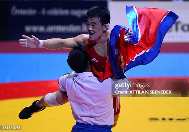 People Republic Korea's Won Chol Yun celebrates his victory over South Korea's Gyujin Choi after their fighting at the men's Greco-Roman style 55 kg...