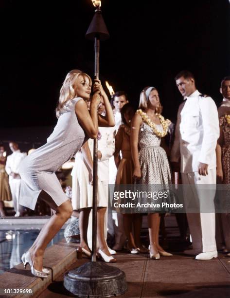 Barbara Bouchet holds onto a torch in a scene from the film 'In Harm's Way', 1965.