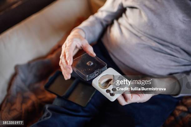 the joy of improved hearing: a photo story capturing the emotional moment a senior lady unpackages her new hearing device on her couch - ear canal stock-fotos und bilder