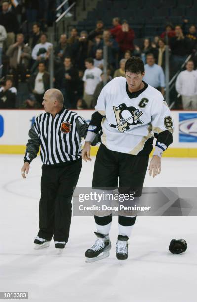 Mario Lemieux of the Pittsburgh Penguins is led from the ice by linesman Ray Scapinello after a fight with Brad Ference of the Florida Panthers at...