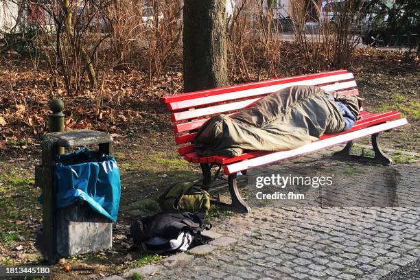 homeless person sleeping on a park bench - obdachlosigkeit stock-fotos und bilder