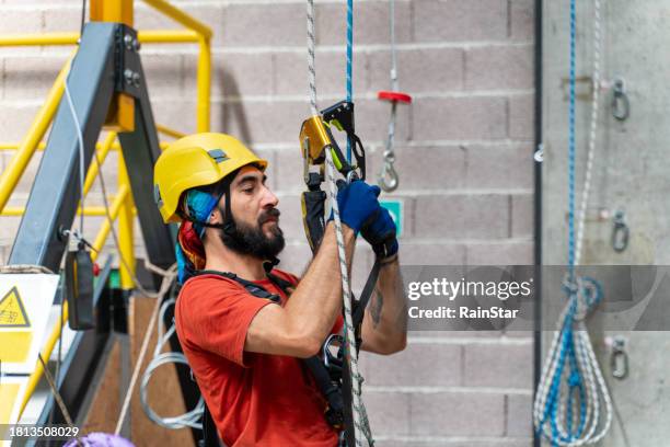 climber wearing his helmet checks the rope before climbing - careerbuilder challenge stock pictures, royalty-free photos & images