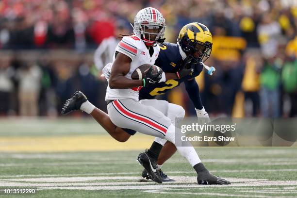 Marvin Harrison Jr. #18 of the Ohio State Buckeyes makes a catch against Will Johnson of the Michigan Wolverines during the third quarter in the game...