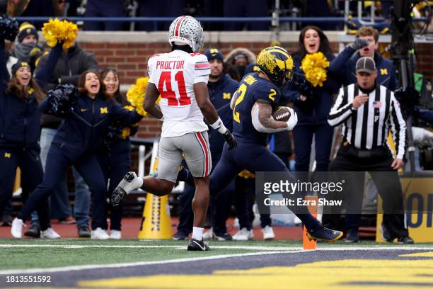Blake Corum of the Michigan Wolverines scores a touchdown against Josh Proctor of the Ohio State Buckeyes during the third quarter in the game at...