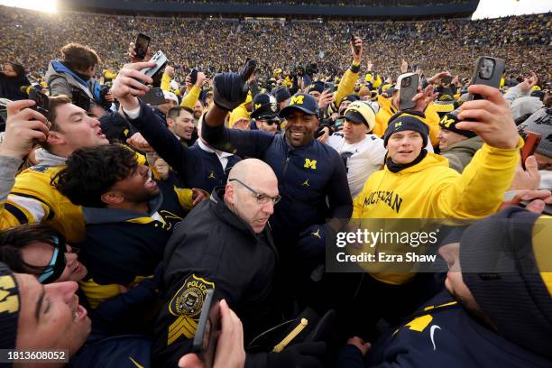 Interim head coach Sherrone Moore of the Michigan Wolverines celebrates with fans on the field after defeating the Ohio State Buckeyes in the game at...