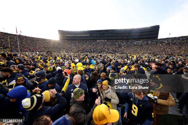 Michigan Wolverines fans celebrate on the field after defeating the Ohio State Buckeyes in the game at Michigan Stadium on November 25, 2023 in Ann...