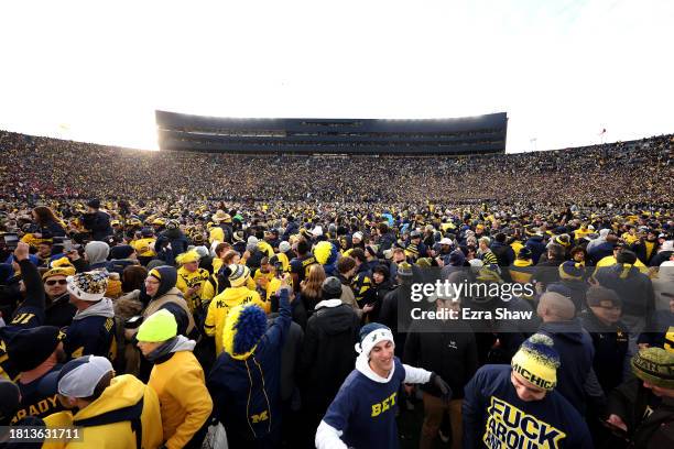 Michigan Wolverines fans celebrate on the field after defeating the Ohio State Buckeyes in the game at Michigan Stadium on November 25, 2023 in Ann...