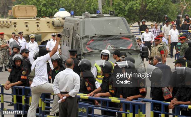 An Egyptian man raises his shoe at the police vehicle carrying Egypt's former interior minister Habib al-Adli in Cairo on May 5, 2011 after a court...