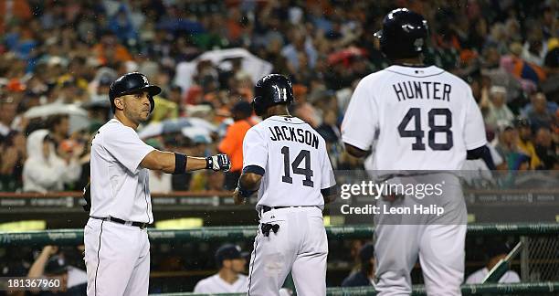 Torii Hunter and Austin Jackson of the Detroit Tigers celebrate with teammate Omar Infante after scoring on a single to centerfield by Andy Dirks...