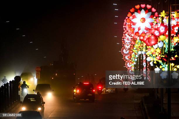 Motorists speed past lighted Christmas lanterns displayed along a street in Manila on November 30, 2023.