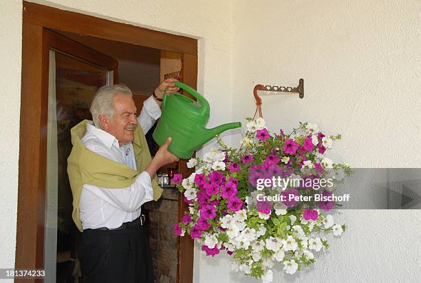 Claus Wilcke, Homestory, Rot am See, Landkreis Schwäbisch Hall, Baden-Württemberg, Deutschland, Europa, Ampel-Pflanze gießen, vor Haustür, Gießkanne,...