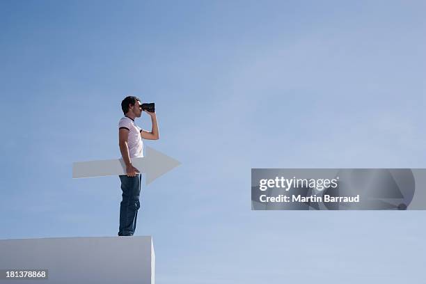 man on pedestal with binoculars and arrow - viewing binoculars stock pictures, royalty-free photos & images