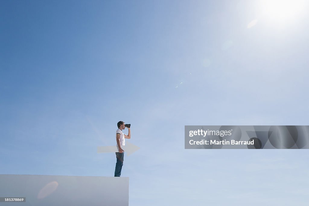 Homem em pedestal com binóculos e Flecha