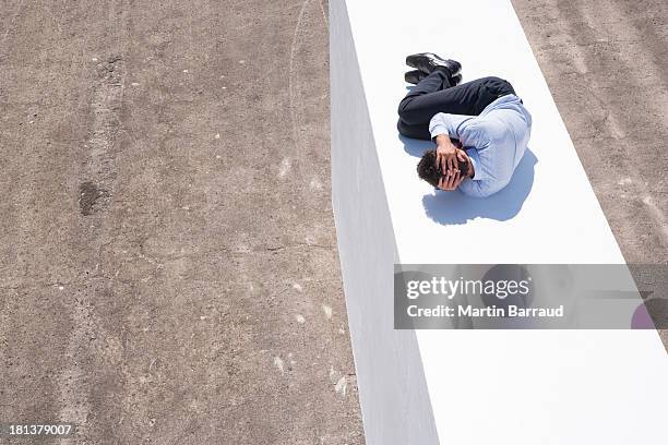 homme d'affaires sur le mur à l'extérieur en position du foetus - position du foetus photos et images de collection