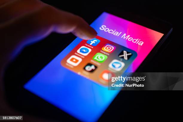 Close-up of a finger is pointing to the Facebook mobile app on a smartphone screen, which is displayed alongside other apps including Instagram,...