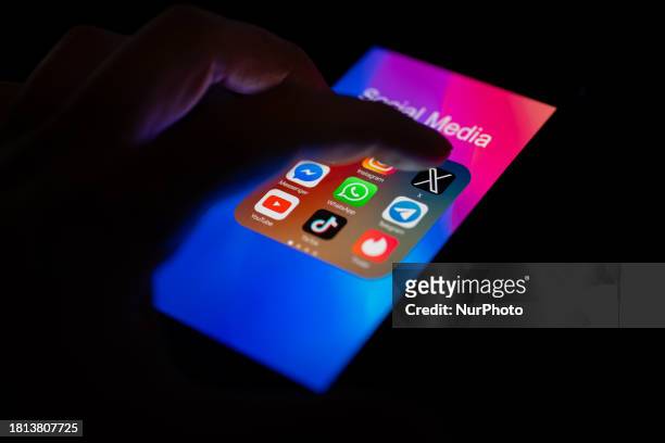 Close-up of a finger is pointing to the Twitter mobile app on a smartphone screen, which is displayed alongside other apps including Instagram,...