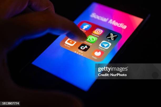 Close-up of a finger is pointing to the TikTok mobile app on a smartphone screen, which is displayed alongside other apps including Instagram,...