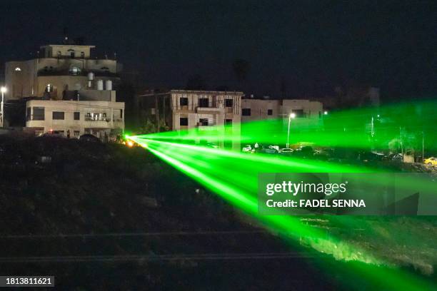 Palestinians direct a laser towards the Ofer military prison located between Ramallah and Beitunia in the occupied West Bank on November 30 before...