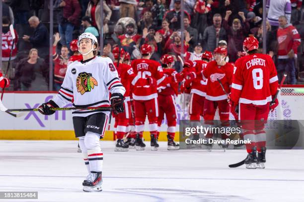 Connor Bedard of the Chicago Blackhawks skates away as the Detroit Red Wings celebrate the win at Little Caesars Arena on November 30, 2023 in...