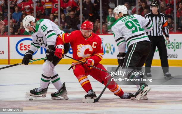 Mikael Backlund of the Calgary Flames skates against Tyler Sequin, Matt Duchene of the Dallas Stars at Scotiabank Saddledome on November 30, 2023 in...