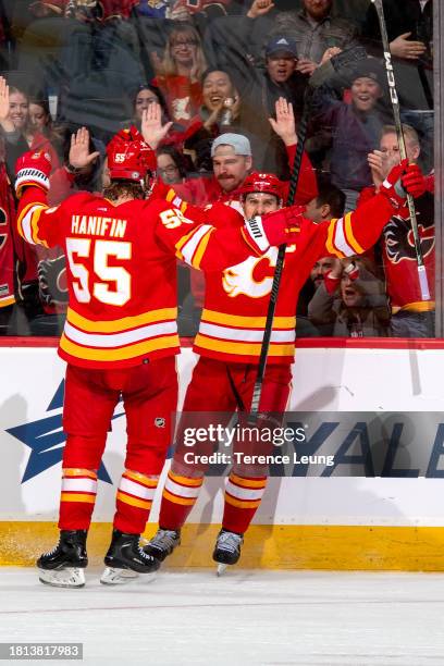 Noah Hanifin, Mikael Backlund of the Calgary Flames celebrate a third period goal against the Dallas Stars at Scotiabank Saddledome on November 30,...