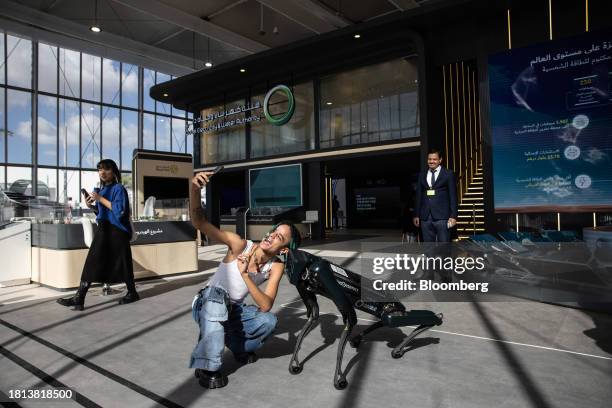 An attendee takes a selfie photograph with a Boston Dynamics Inc. Spot robot inside the Energy Transition hub within the Green Zone on the opening...