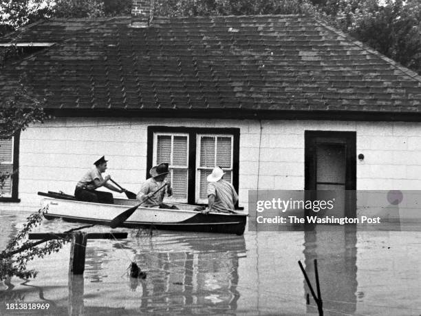 Firemen use boats to check the home of Rudolph Washington on Minnesota Avenue NE, Washington, DC on August 9, 1959.