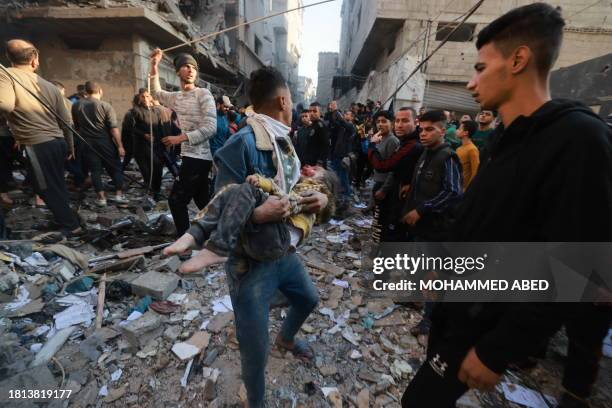 Graphic content / A Palestinian youth carries a badly wounded child as poeple rush out of a bombarded area in the Rafah refugee camp in the southern...