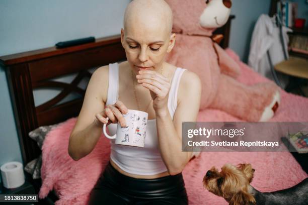 bald woman with breast cancer drinks pills - stress test stockfoto's en -beelden