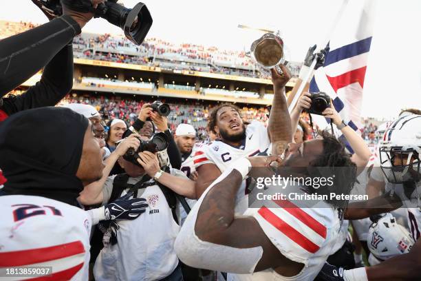 Running back Jonah Coleman of the Arizona Wildcats celebrates with the Territorial Cup following the NCAAF game at Mountain America Stadium on...