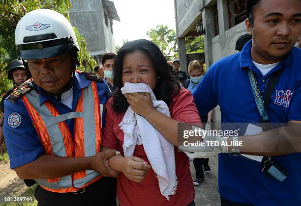 An injured resident is helped by rescuers after a mortar shell believed to be from the Muslim rebels' position hit her house as government forces...