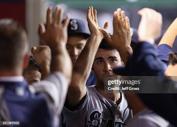 Nick Franklin of the Seattle Mariners receives high fives in the dugout after scoring a run on a base hit by Michael Saunders in the seventh inning...