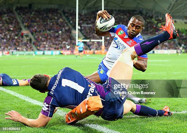 Akuila Uate of the Knights fends off a tackle from Billy Slater of the Storm to score a try during the NRL Second Semi Final match between the...