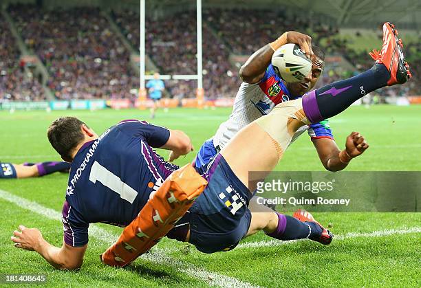 Akuila Uate of the Knights fends off a tackle from Billy Slater of the Storm to score a try during the NRL Second Semi Final match between the...