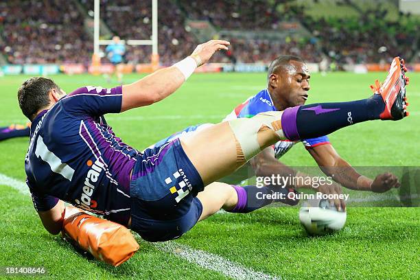 Akuila Uate of the Knights fends off a tackle from Billy Slater of the Storm to score a try during the NRL Second Semi Final match between the...