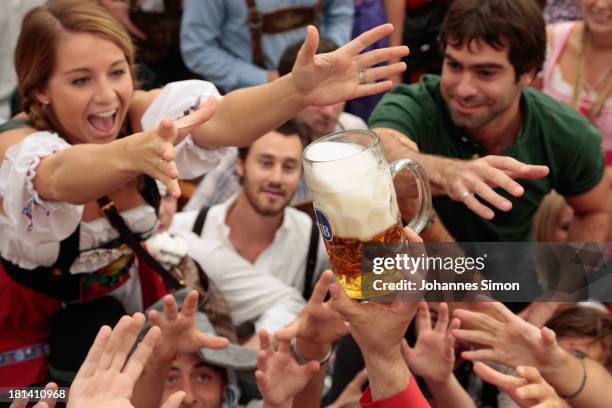 Revellers reach for the first beer mug at Hofbraeuhaus beer tent during day 1 of the Oktoberfest 2013 beer festival at Theresienwiese on September...