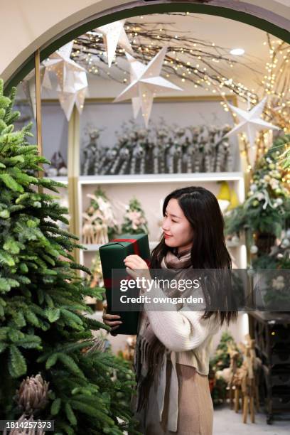 young asian woman shopping at christmas market - boxing day shopping in winter stockfoto's en -beelden