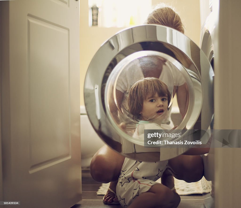 Small boy with his mother in front of a washing ma