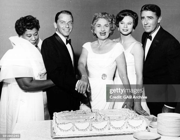 American singer and actor Frank Sinatra and English actress Hermione Gingold cutting their joint birthday cake, December 1959. Left to right: singer...