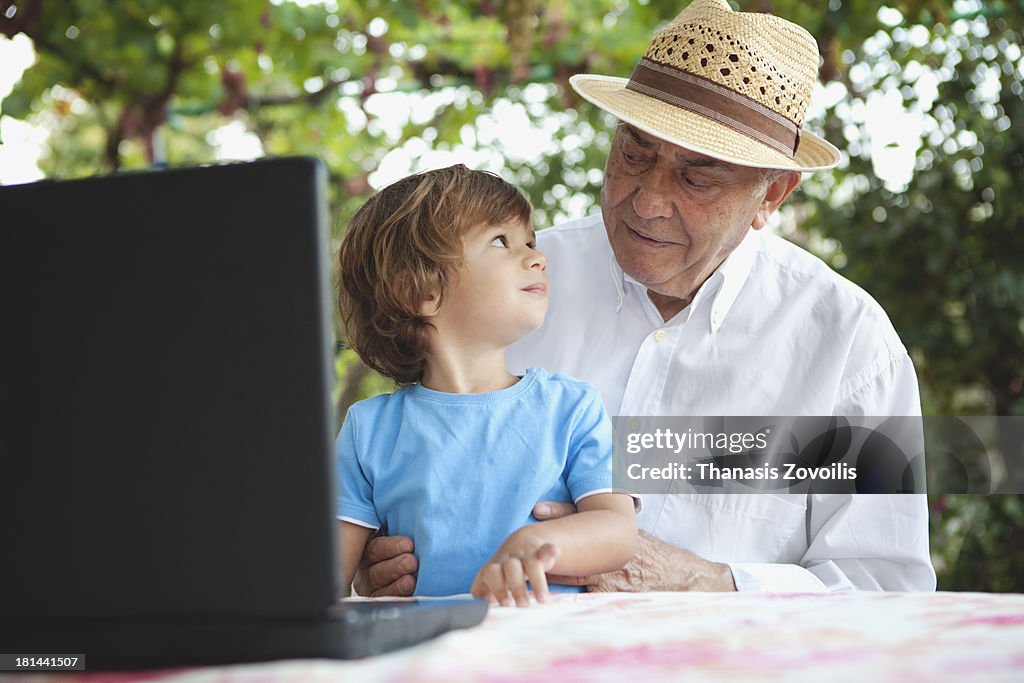Small boy with his grandfather in front of a lapto