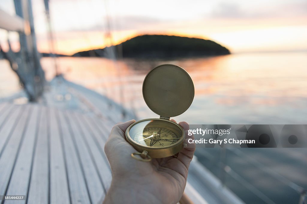 Antique compass at sunrise with sailboat