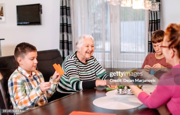 multi-generation family members having fun at home making origami using paper sheet - origami instructions stock pictures, royalty-free photos & images