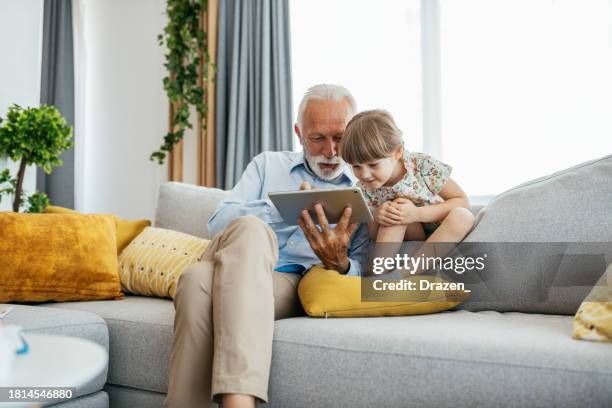 nonno e nipote a casa, giocando a videogiochi su tablet digitale - nipoti maschi e femmine foto e immagini stock