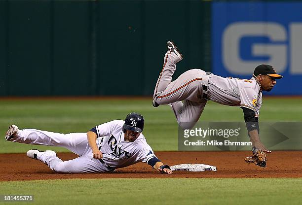 Alexi Casilla of the Baltimore Orioles turns a double play as David DeJesus of the Tampa Bay Rays slides into second during a game at Tropicana Field...