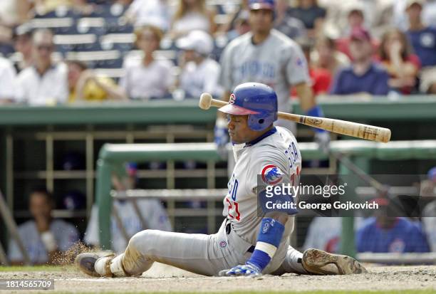 Sammy Sosa of the Chicago Cubs sits on the ground after ducking out of the way of a close pitch that almost hit him while batting against the...