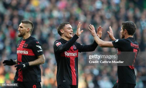 Robert Andrich, Florian Wirtz and Jonas Hofmann of Bayer Leverkusen celebrate Bayer Leverkusen's first goal, an own-goal scored by Olivier Deman of...