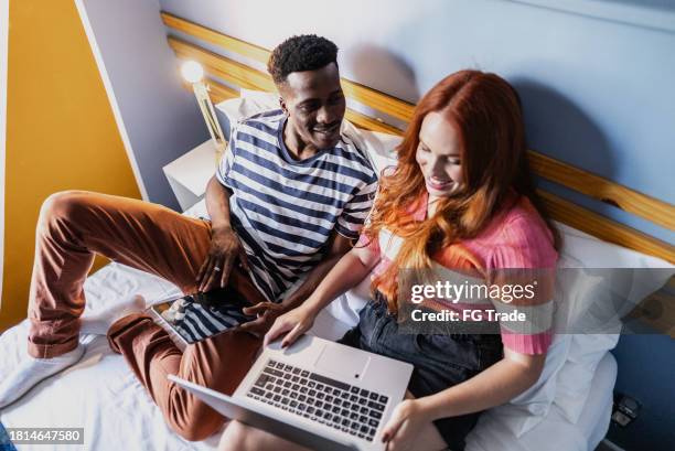 couple talking and using technologies in bedroom at hostel - man in suite holding tablet stockfoto's en -beelden