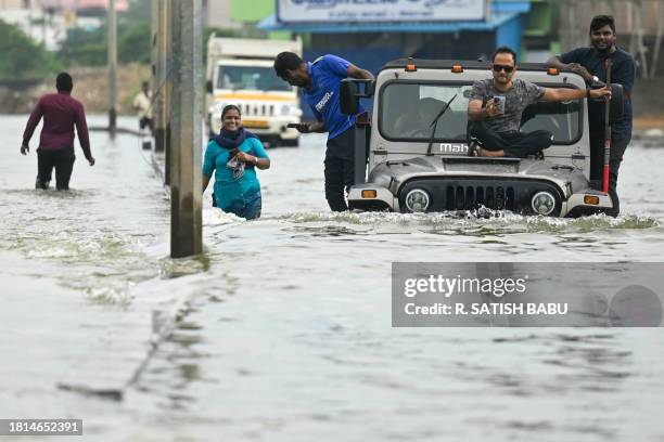 Commuters wade across a flooded street after heavy rains in Chennai on December 1, 2023.
