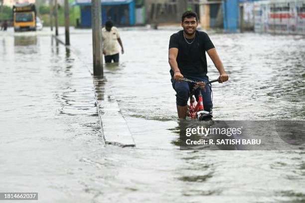 Commuters wade across a flooded street after heavy rains in Chennai on December 1, 2023.