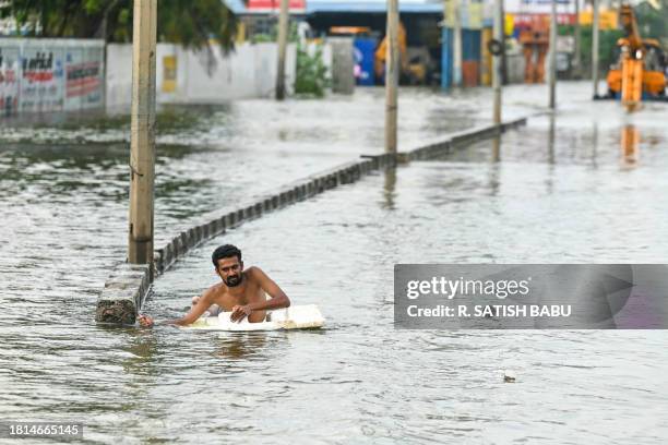 Man wades across a flooded street after heavy rains in Chennai on December 1, 2023.